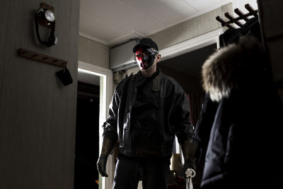 Demon wearing mask standing by doorway in cabin