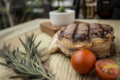 Close-up of tenderloin steak by rosemary on wooden table