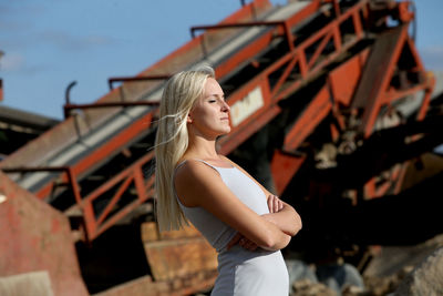 Woman standing with eyes closed against machinery