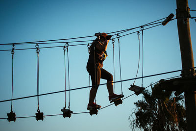 Low angle view of girl walking on rope against sky