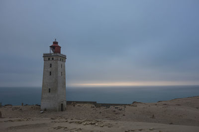 Lighthouse by sea against sky