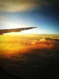 Cropped image of airplane flying over cloudscape during sunset