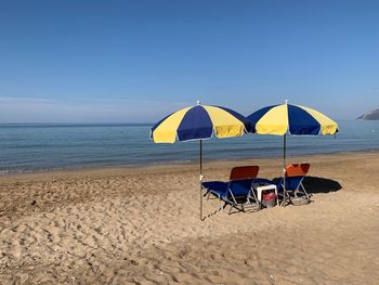 Deck chairs and parasols on beach against sky