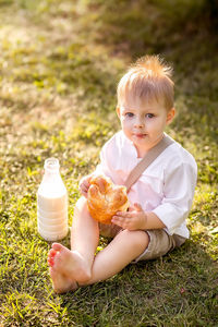 Full length portrait of boy sitting on field