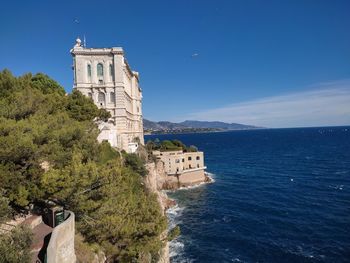 Historic building by sea against blue sky