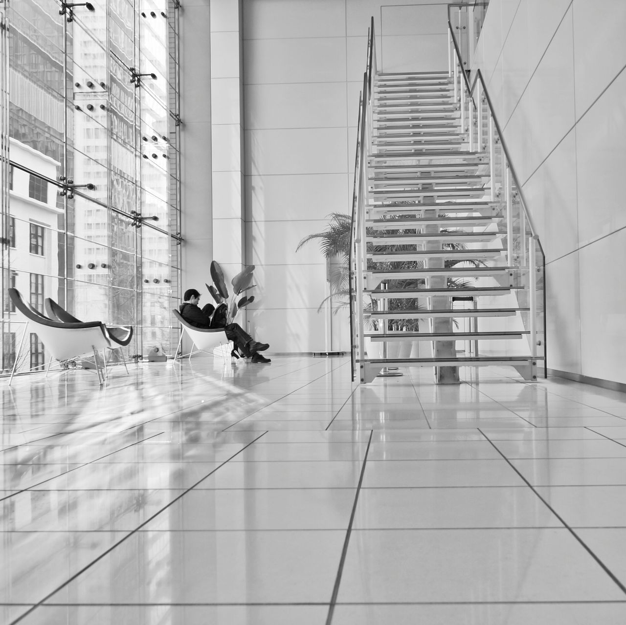 indoors, architecture, built structure, tiled floor, tile, flooring, building exterior, wall - building feature, window, full length, building, wall, reflection, glass - material, door, modern, day, walking, corridor, one person