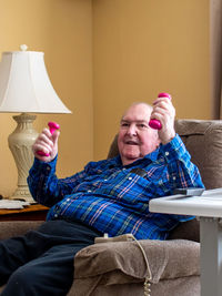 An elderly male sits in his lift chair and exercises with a small pair of hand weights