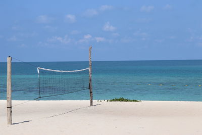 Volleyball net at sea shore against sky