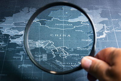 Cropped hand holding magnifying glass on map