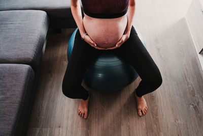 Low section of pregnant woman exercising while sitting at home