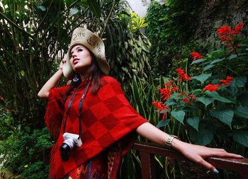 Young woman wearing hat standing against plants