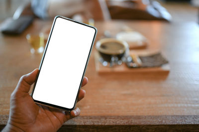 Close-up of hand holding mobile phone on table
