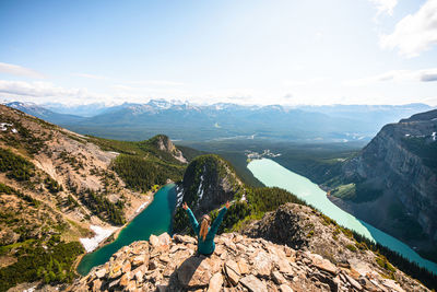 Hiker celebrating above lake louise and lake agnes on devil's thumb