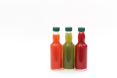 Close-up of multi colored bottles against white background