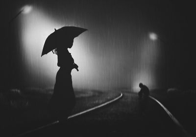 Silhouette woman with umbrella walking in rain