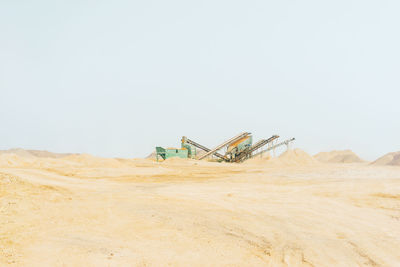 Machinery at quarry against clear sky