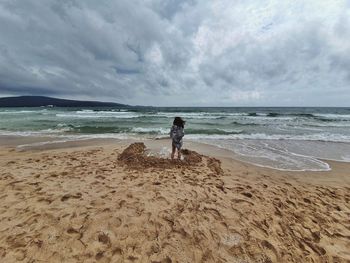 Rear view of woman on beach against sky