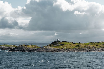 Lighthouse amidst sea and buildings against sky