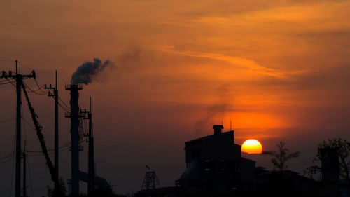 Low angle view of silhouette building against orange sky