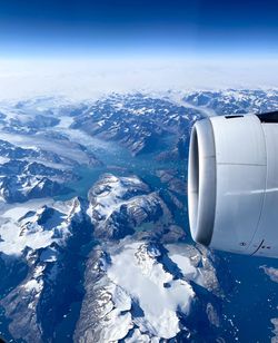 Airplane flying over snowcapped mountains against sky