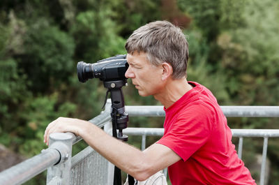 Side view of man photographing on railing