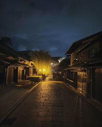 Empty illuminated street amidst buildings at night