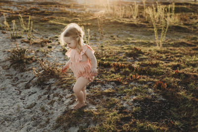 Lifestyle portrait of toddler girl walking away at beach sunset