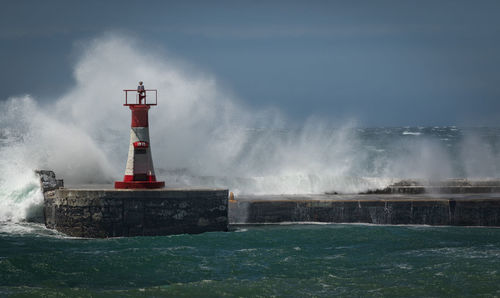 Lighthouse by sea against sky