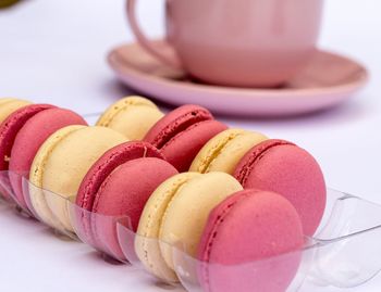 Close-up of macaroons in plastic container by cup on table