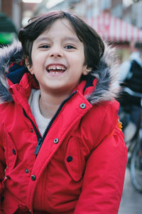 Portrait of cute 4 year old boy wearing red jacket and smiling
