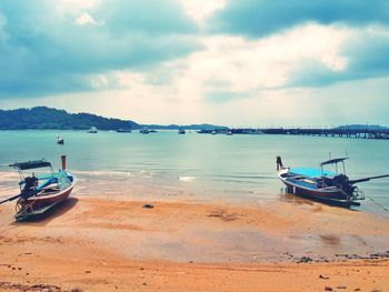 Boats in sea against cloudy sky