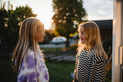 Smiling female friends with blond hair looking at each other