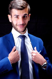 Portrait of smiling businessman against black background