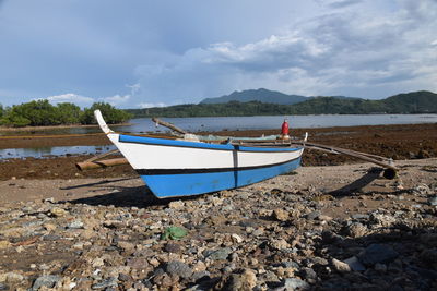 Boat moored on beach against sky