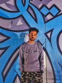 Portrait of boy standing against graffiti wall