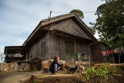 Man sitting outside building against sky