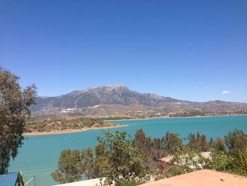 Scenic view of sea and mountains against clear blue sky