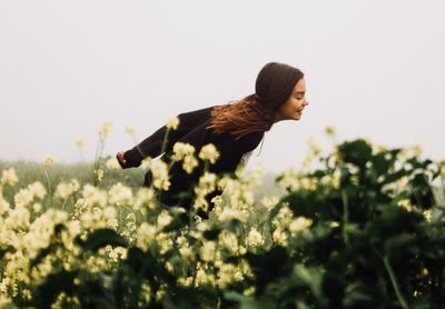 Side view of girl running by plants against sky