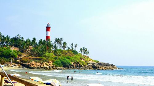 Lighthouse on beach against blue sky