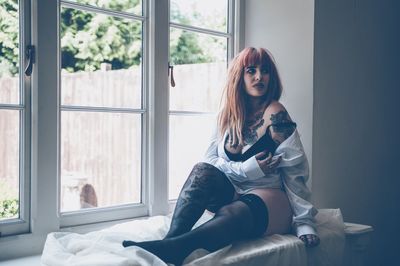 Hipster woman sitting on window sill