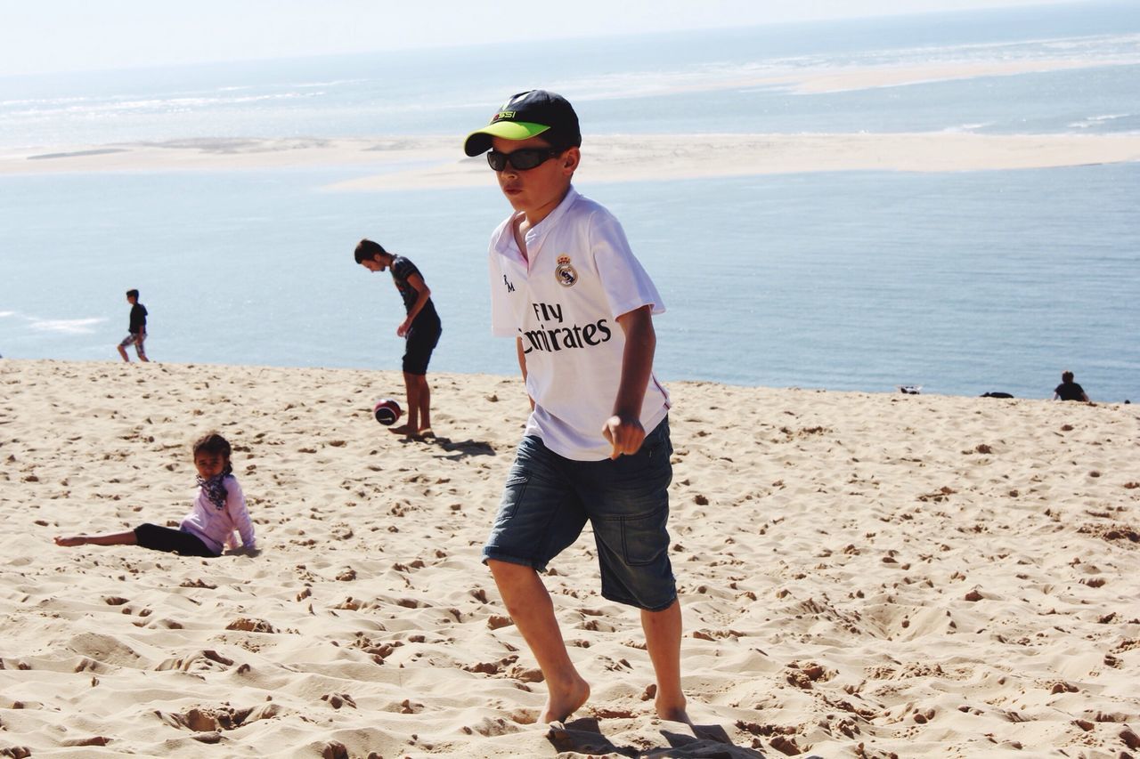 beach, sea, sand, shore, lifestyles, full length, leisure activity, water, vacations, casual clothing, boys, horizon over water, person, childhood, sunlight, sky, summer, enjoyment