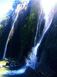 Scenic view of waterfall against sky