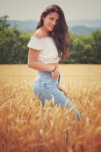 Portrait of smiling young woman standing in field