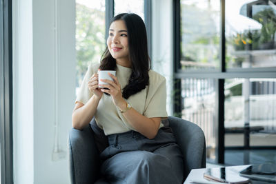 Young woman using mobile phone while sitting in office