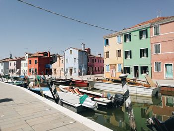 Boats moored on canal by buildings against sky in city