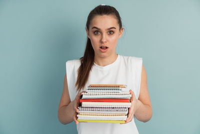 Portrait of young woman standing against blue background