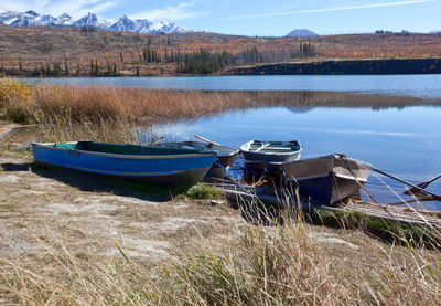 Boats moored on shore by lake