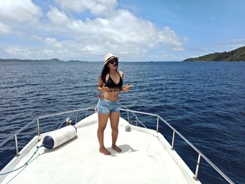 Rear view of woman sitting on boat in sea against sky