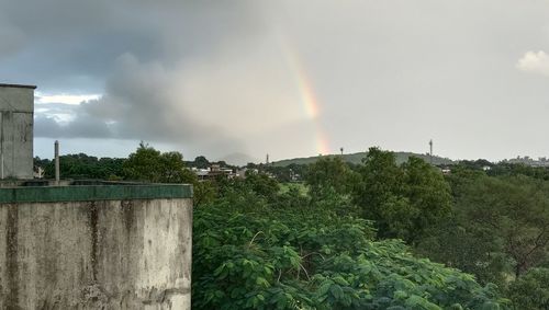 Scenic view of rainbow over trees and buildings