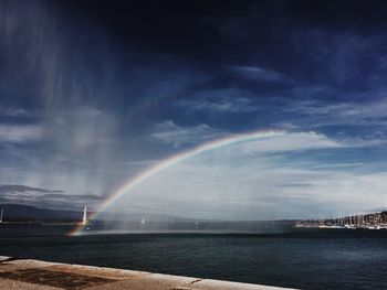 Scenic view of rainbow over sea against sky